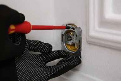 Photo of Electrician with screwdriver repairing power socket, closeup