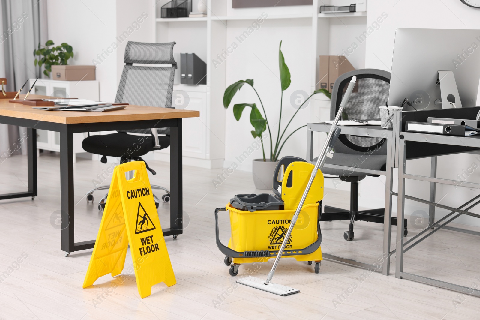 Photo of Cleaning service. Mop, wet floor sign and bucket in office