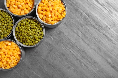 Open tin cans of conserved vegetables on grey table, flat lay with space for text