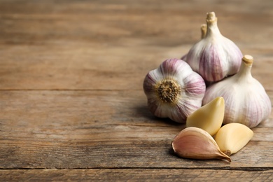Photo of Fresh organic garlic on wooden table. Space for text