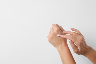Photo of Woman applying cosmetic cream onto hand on white background, closeup. Space for text