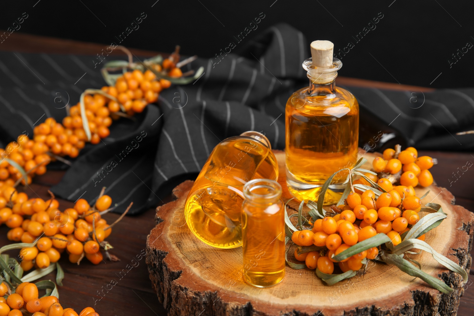 Photo of Natural sea buckthorn oil and fresh berries on wooden table