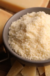 Photo of Delicious grated parmesan cheese in bowl on wooden table, closeup