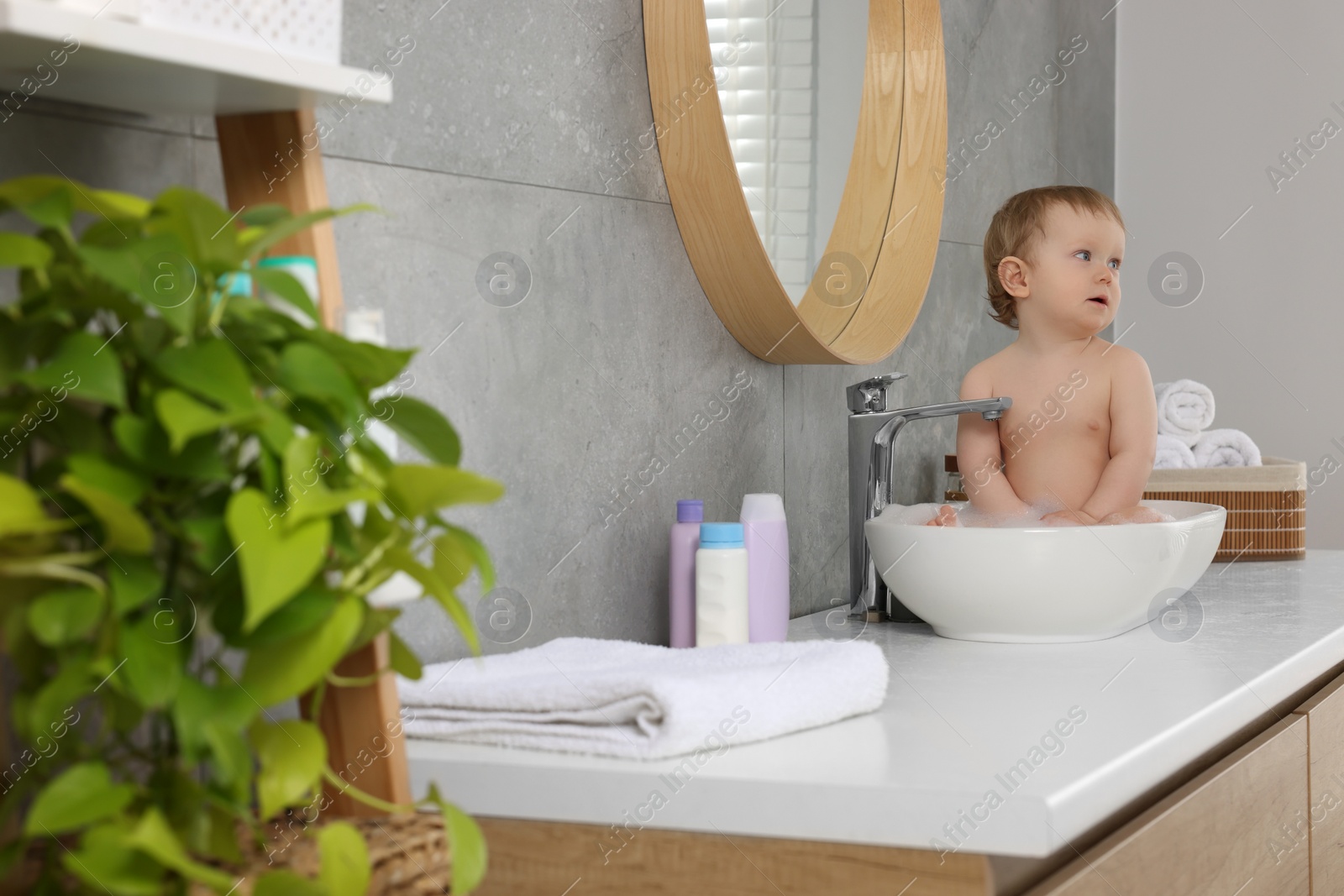 Photo of Cute little baby bathing in sink at home