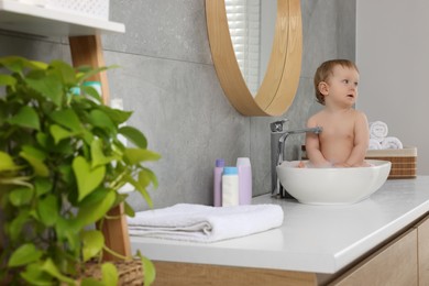 Cute little baby bathing in sink at home