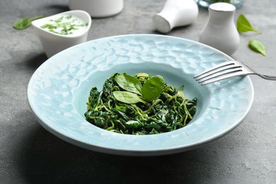 Photo of Tasty cooked spinach on grey table. Healthy food