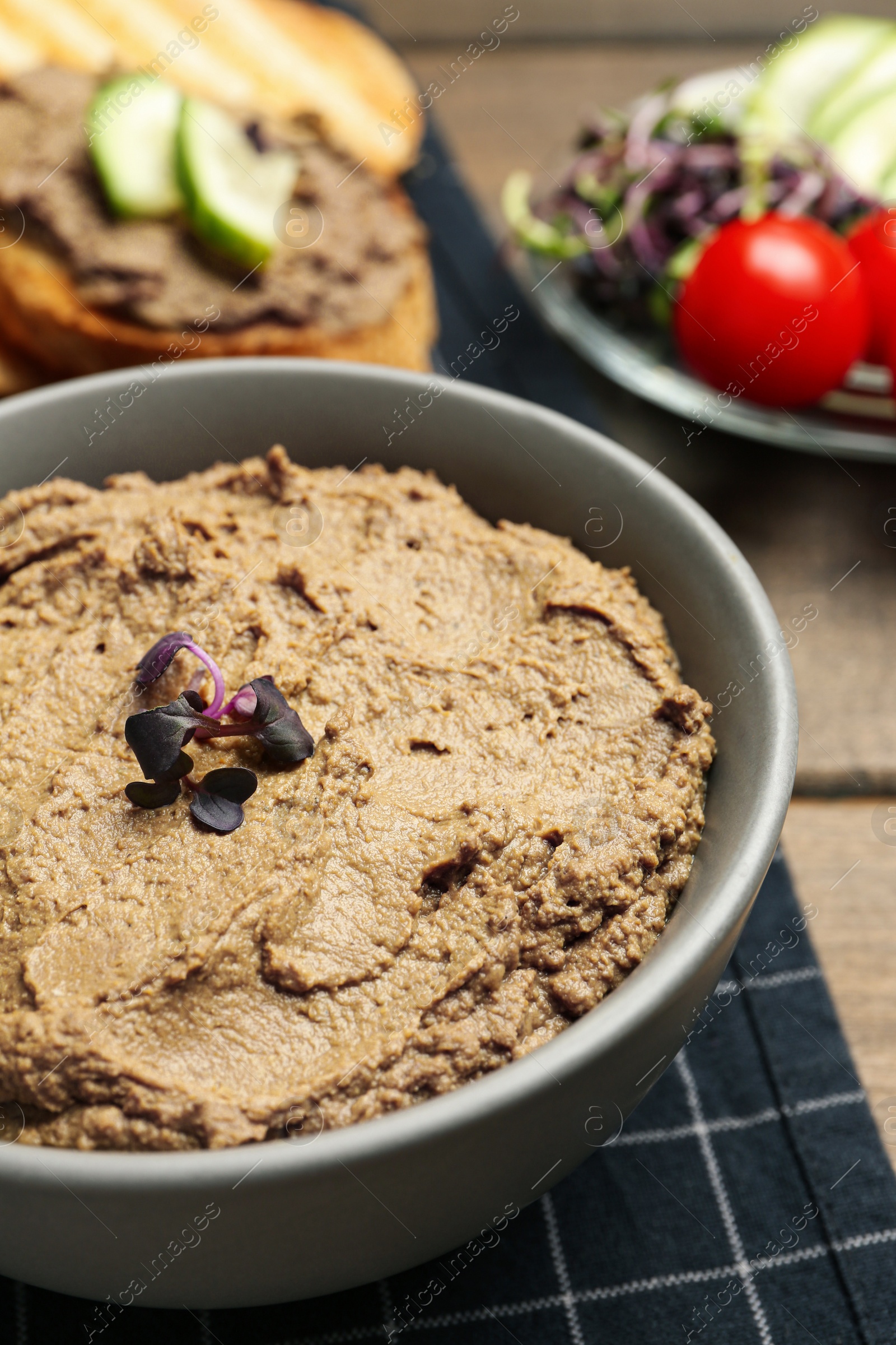 Photo of Bowl with delicious liver pate on wooden table, closeup