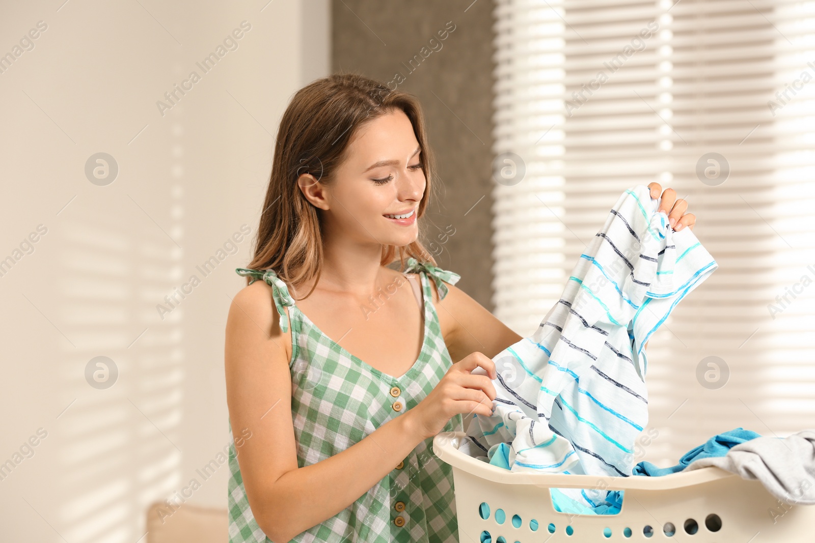 Photo of Pretty teenager with clean laundry before ironing at home