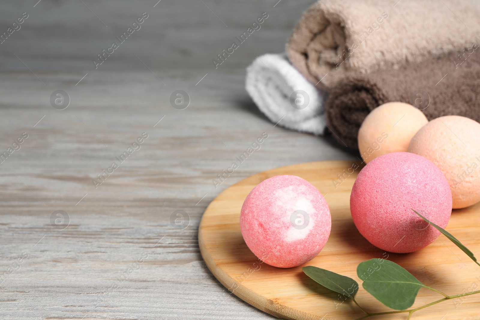 Photo of Beautiful aromatic bath bombs and green branch on light wooden table, space for text