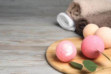 Beautiful aromatic bath bombs and green branch on light wooden table, space for text