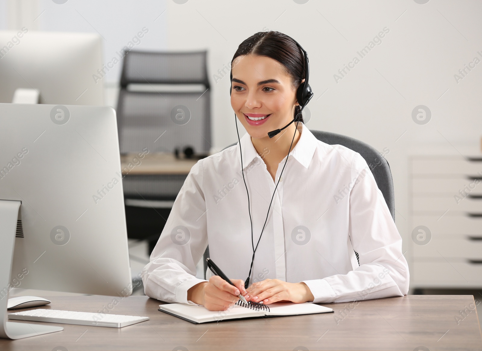 Photo of Hotline operator with headset and notebook working in office