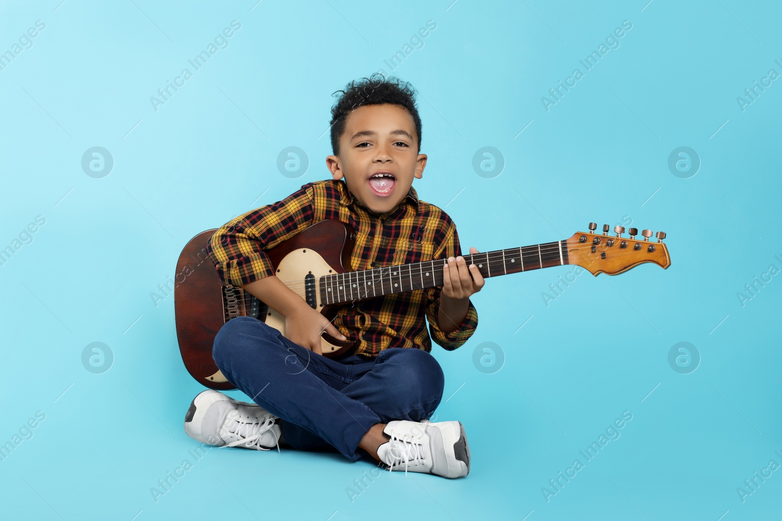 Photo of Cute African-American boy with electric guitar on turquoise background