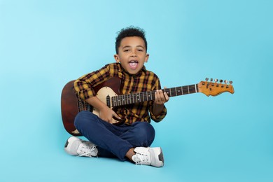 Photo of Cute African-American boy with electric guitar on turquoise background