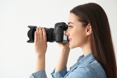 Female photographer with camera on light background