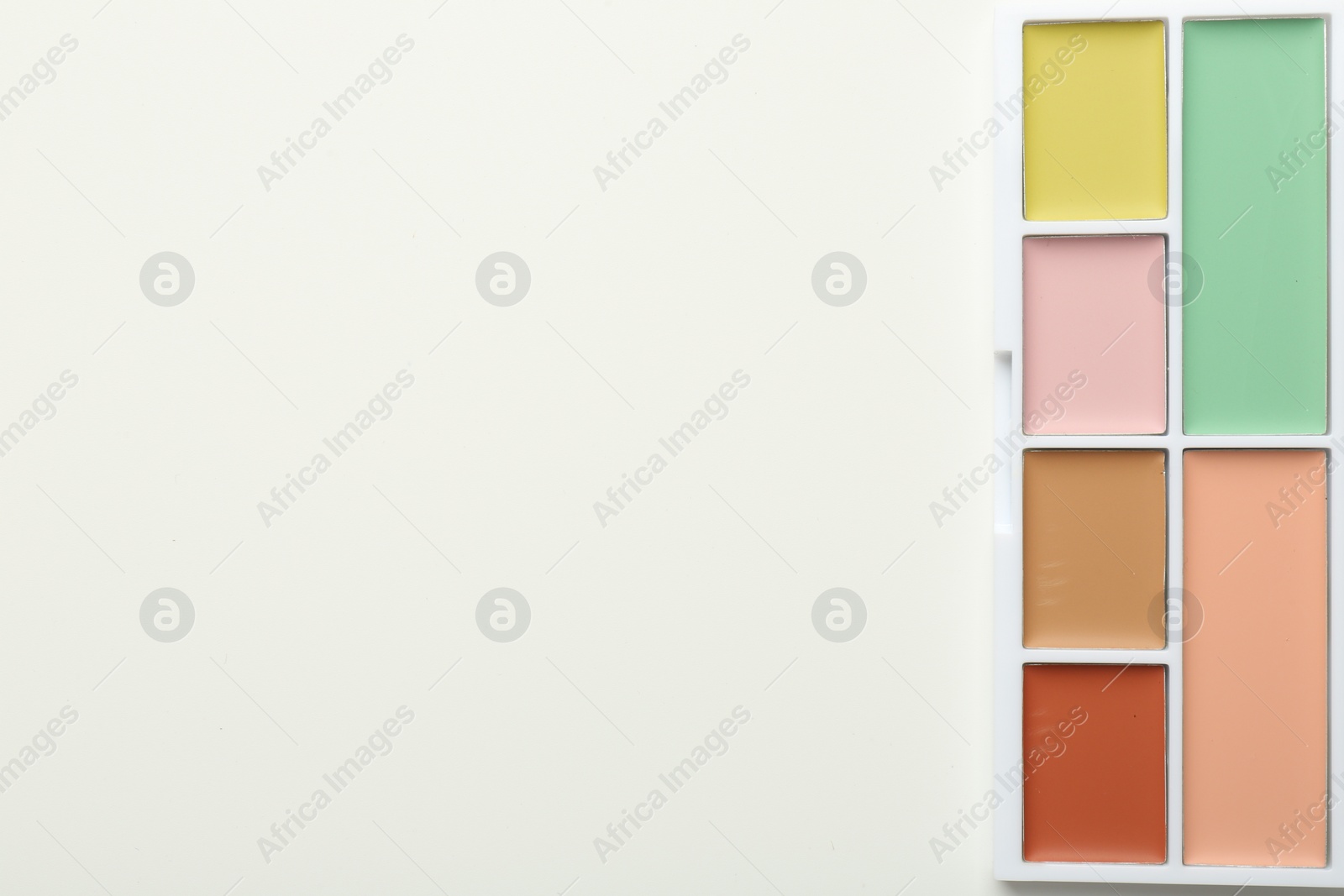 Photo of Colorful correcting concealer palette on white background, top view