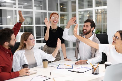 Photo of Team of employees joining hands in office