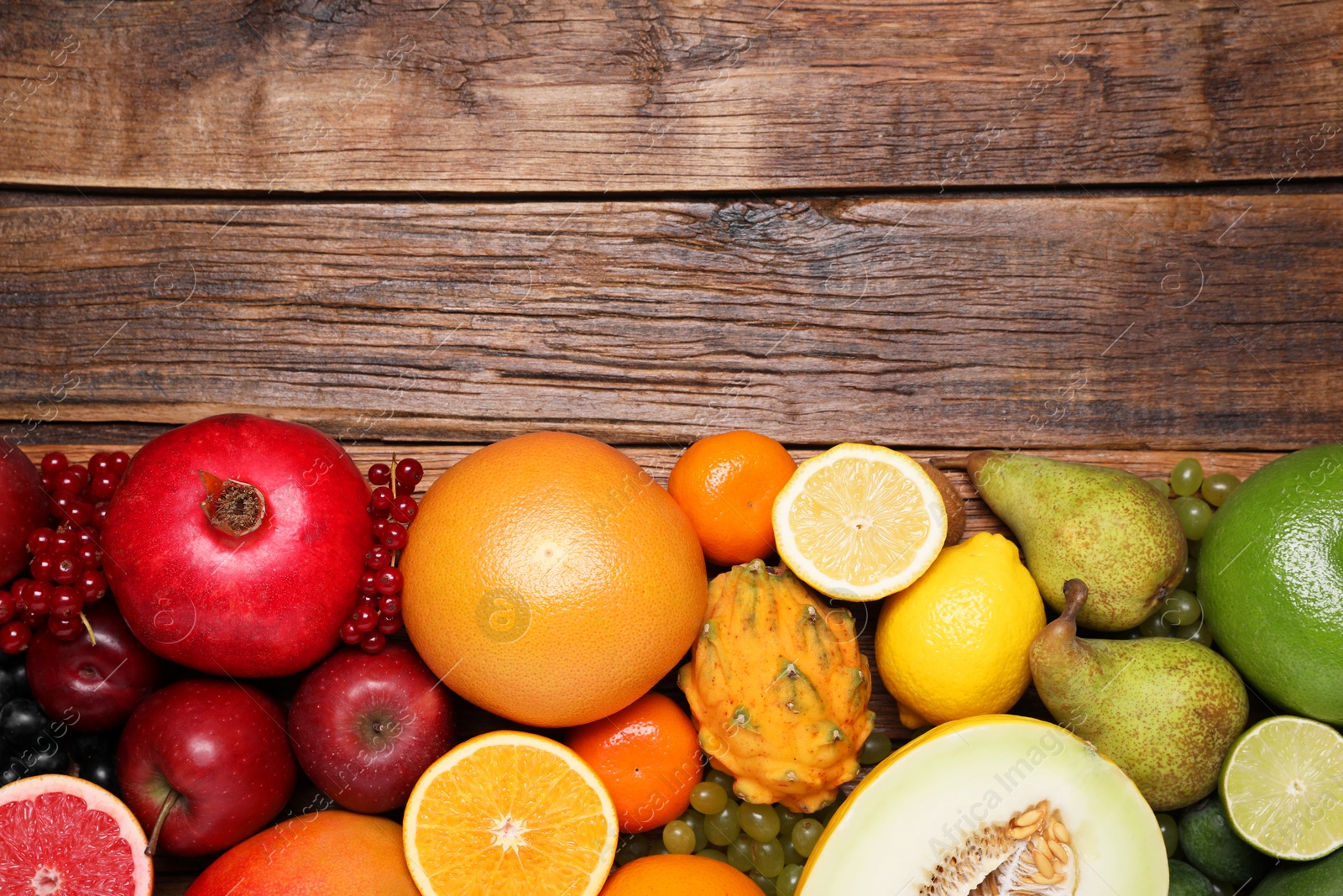 Photo of Many different fresh fruits and berries on wooden table, flat lay. Space for text