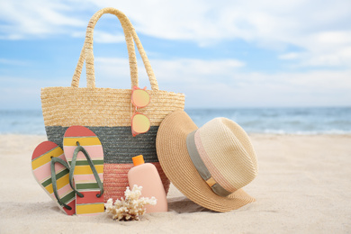 Photo of Different stylish beach objects and coral on sand near sea