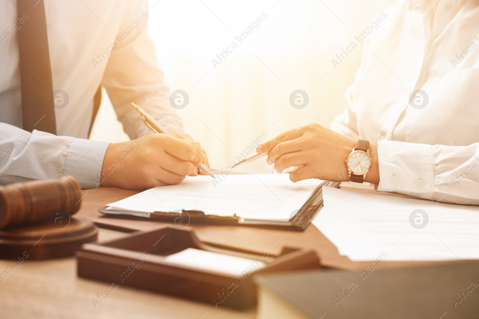 Image of Lawyer pointing at document and client putting signature at table in office, closeup