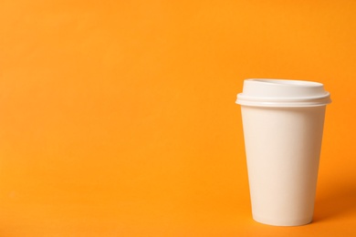 Photo of Takeaway paper coffee cup on orange background. Space for text