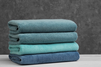 Photo of Stack of soft clean towels on table against grey background