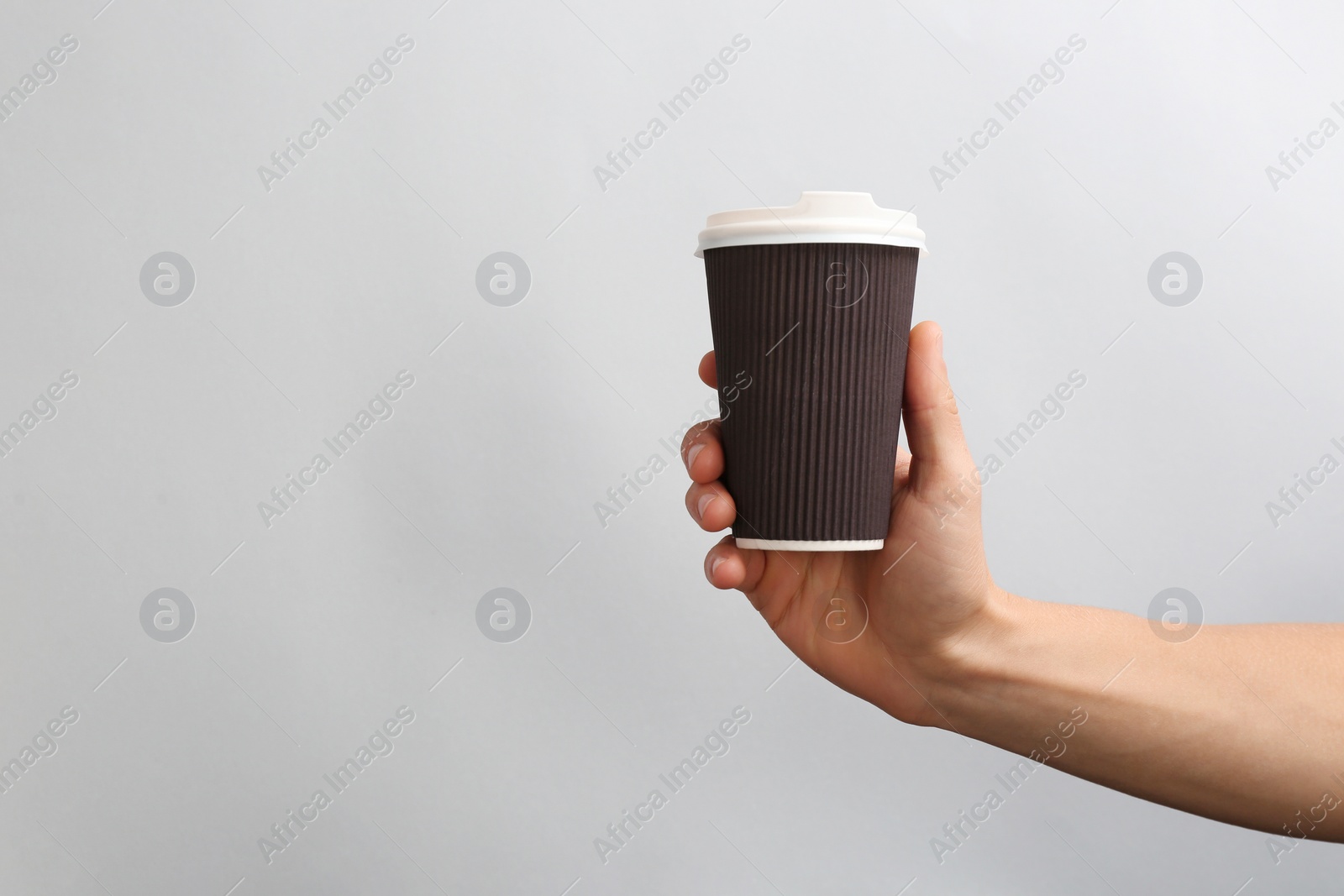 Photo of Man holding takeaway paper coffee cup on light background. Space for design