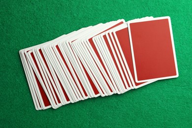 Photo of Deck of playing cards on green table, top view. Poker game