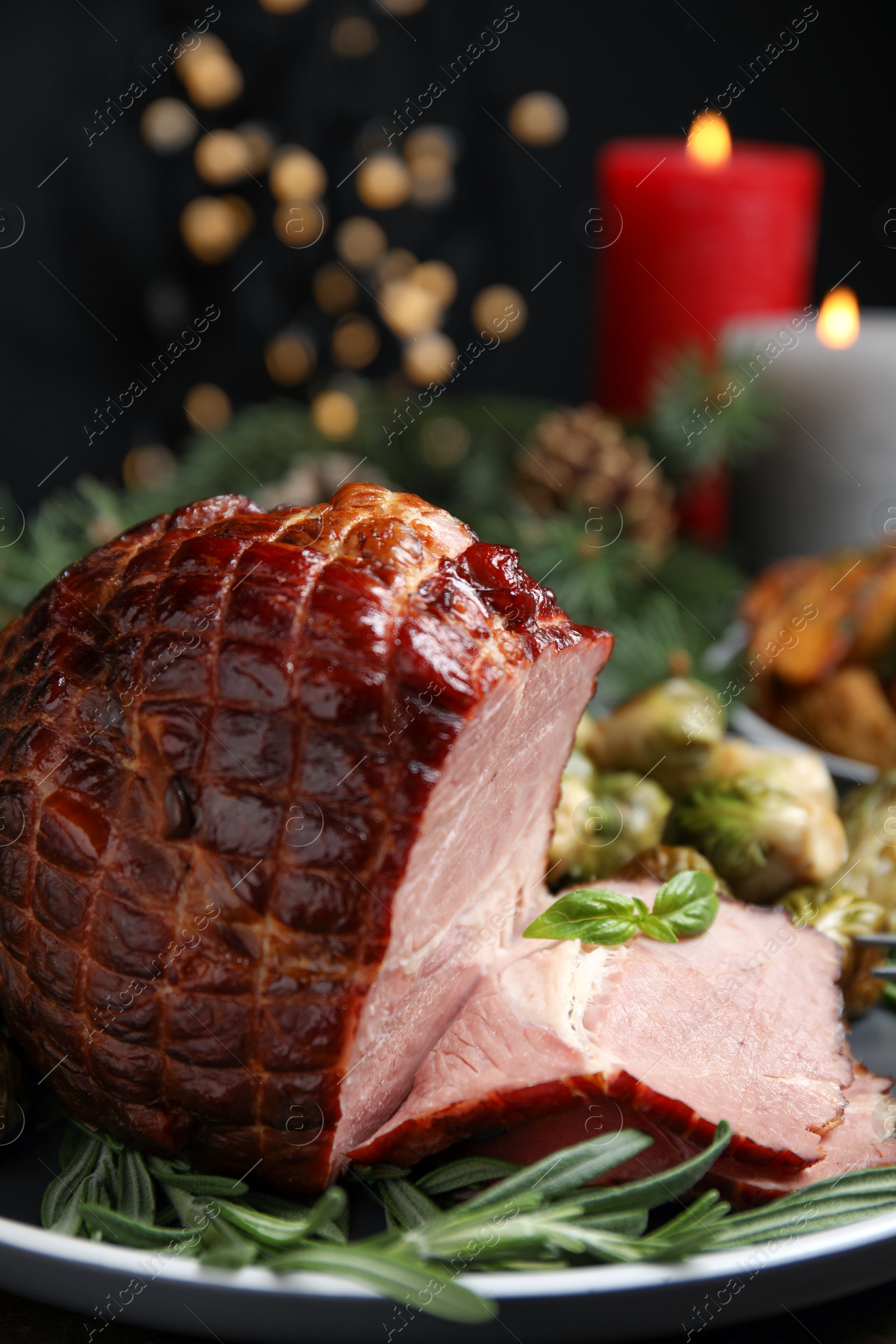 Photo of Delicious ham served with rosemary on plate against blurred festive lights. Christmas dinner