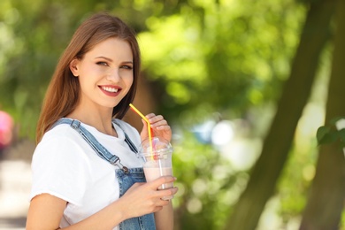 Photo of Young woman with cup of delicious milk shake outdoors