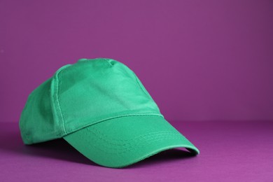 Photo of Baseball cap on purple background, space for text