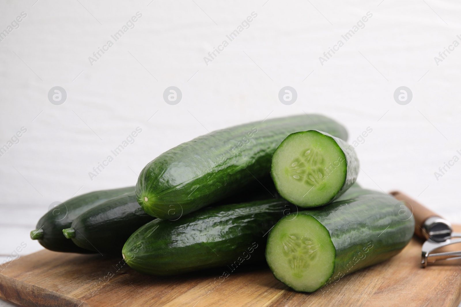 Photo of Many fresh cucumbers on wooden board, closeup