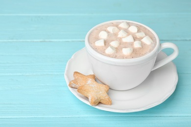 Composition with delicious cacao drink in cup on turquoise wooden background