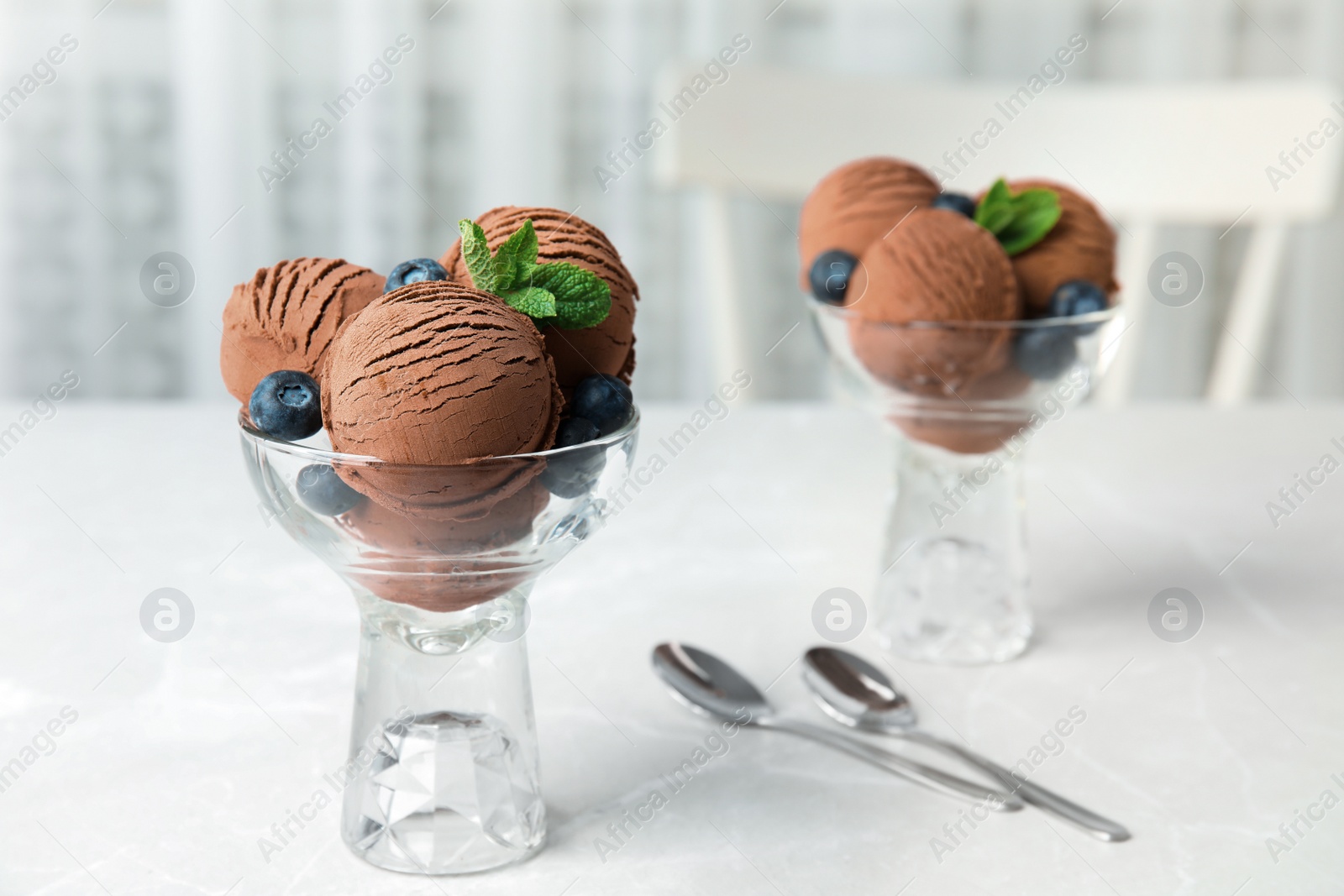 Photo of Glass bowls of chocolate ice cream and blueberries served on light table. Space for text