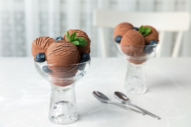 Photo of Glass bowls of chocolate ice cream and blueberries served on light table. Space for text