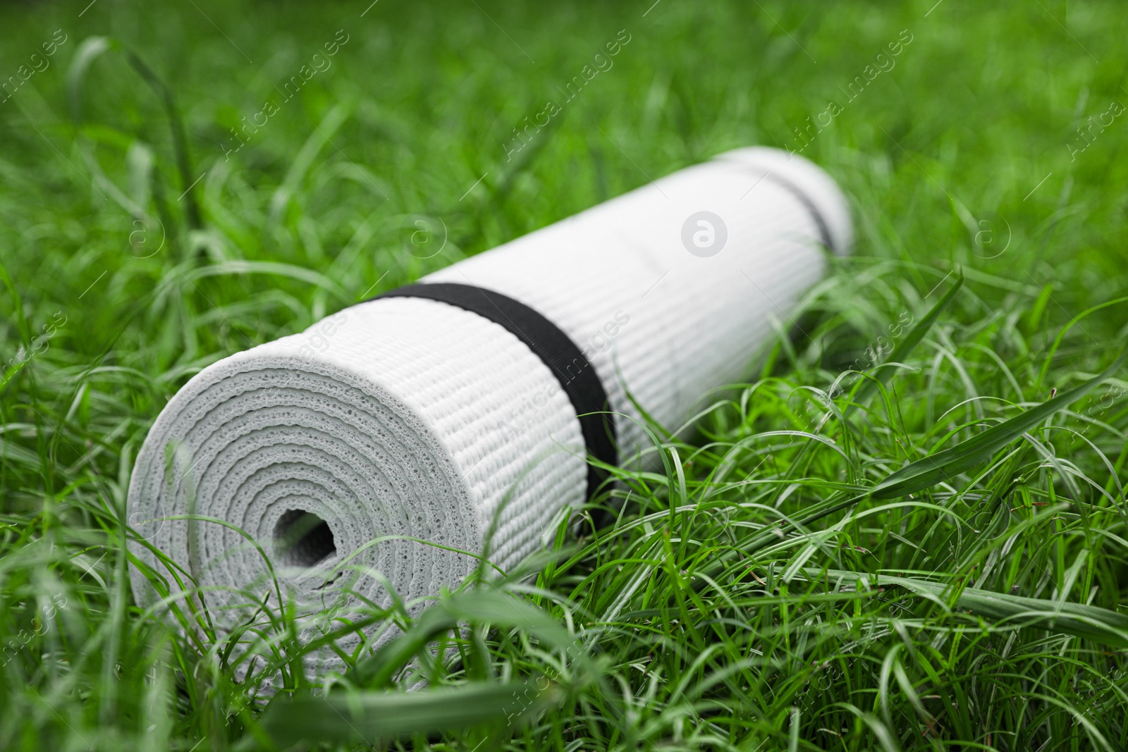 Photo of White karemat or fitness mat on green grass outdoors, closeup