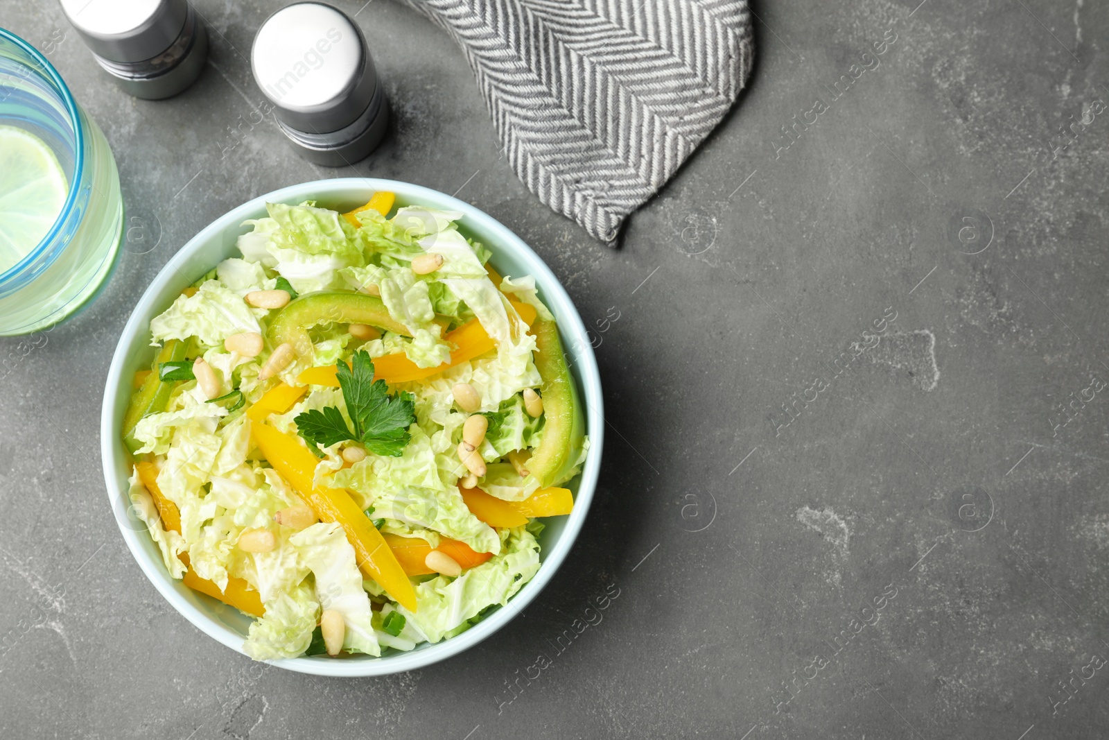 Photo of Bowl of fresh cabbage salad with bell pepper on grey table, top view. Space for text