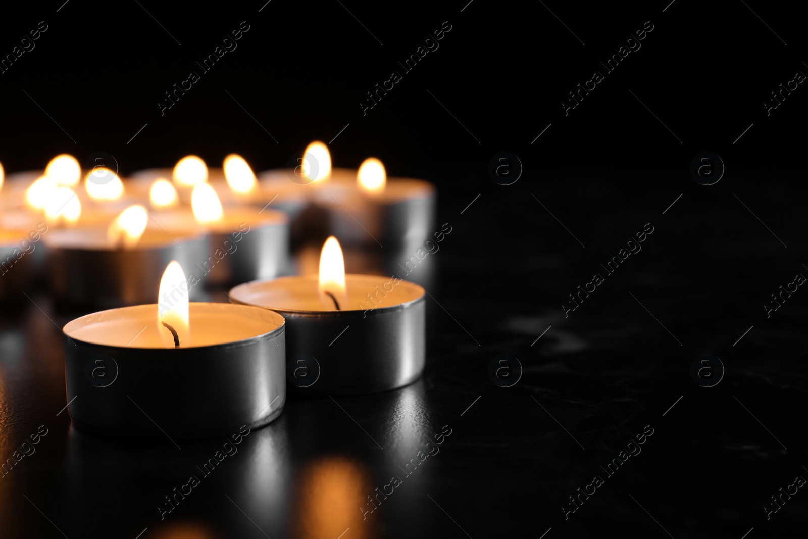 Photo of Burning candles on table in darkness, space for text. Funeral symbol