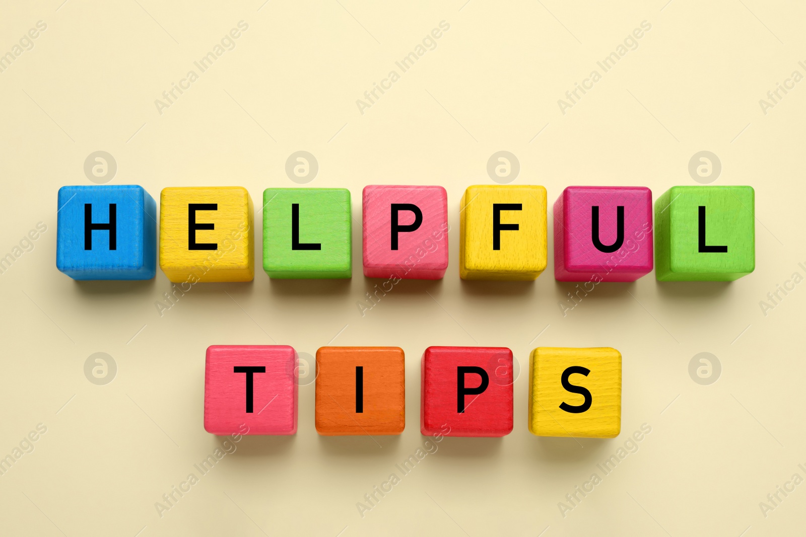 Photo of Phrase Helpful Tips made of colorful cubes with letters on beige background, top view