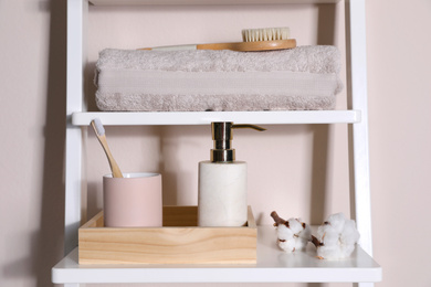 Shelving unit with toiletries near light wall indoors. Bathroom interior element