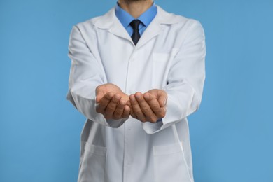 Photo of Dentist holding something on light blue background, closeup