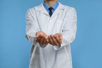 Dentist holding something on light blue background, closeup