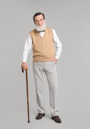 Senior man with walking cane on light gray background