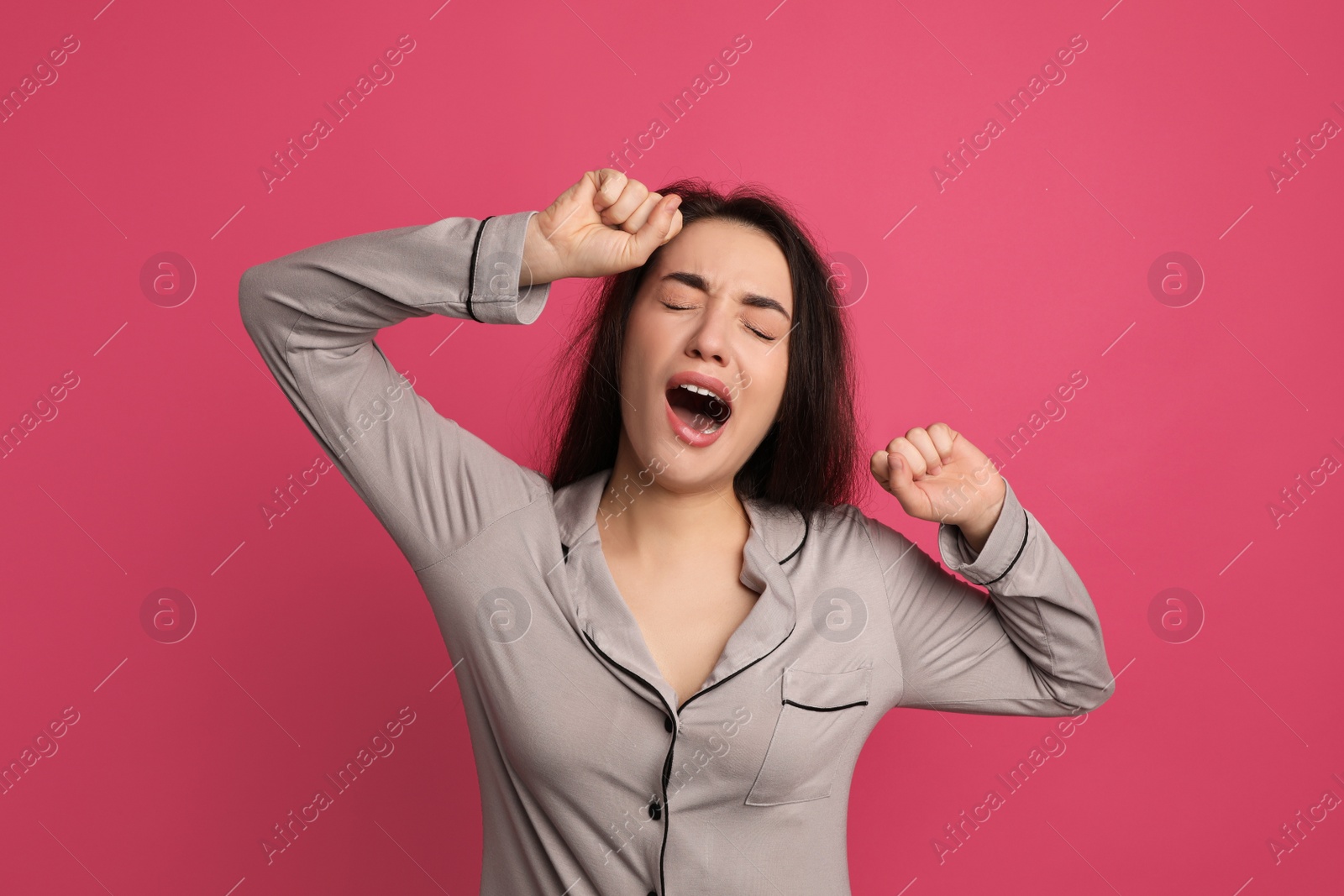 Photo of Young tired woman yawning on pink background