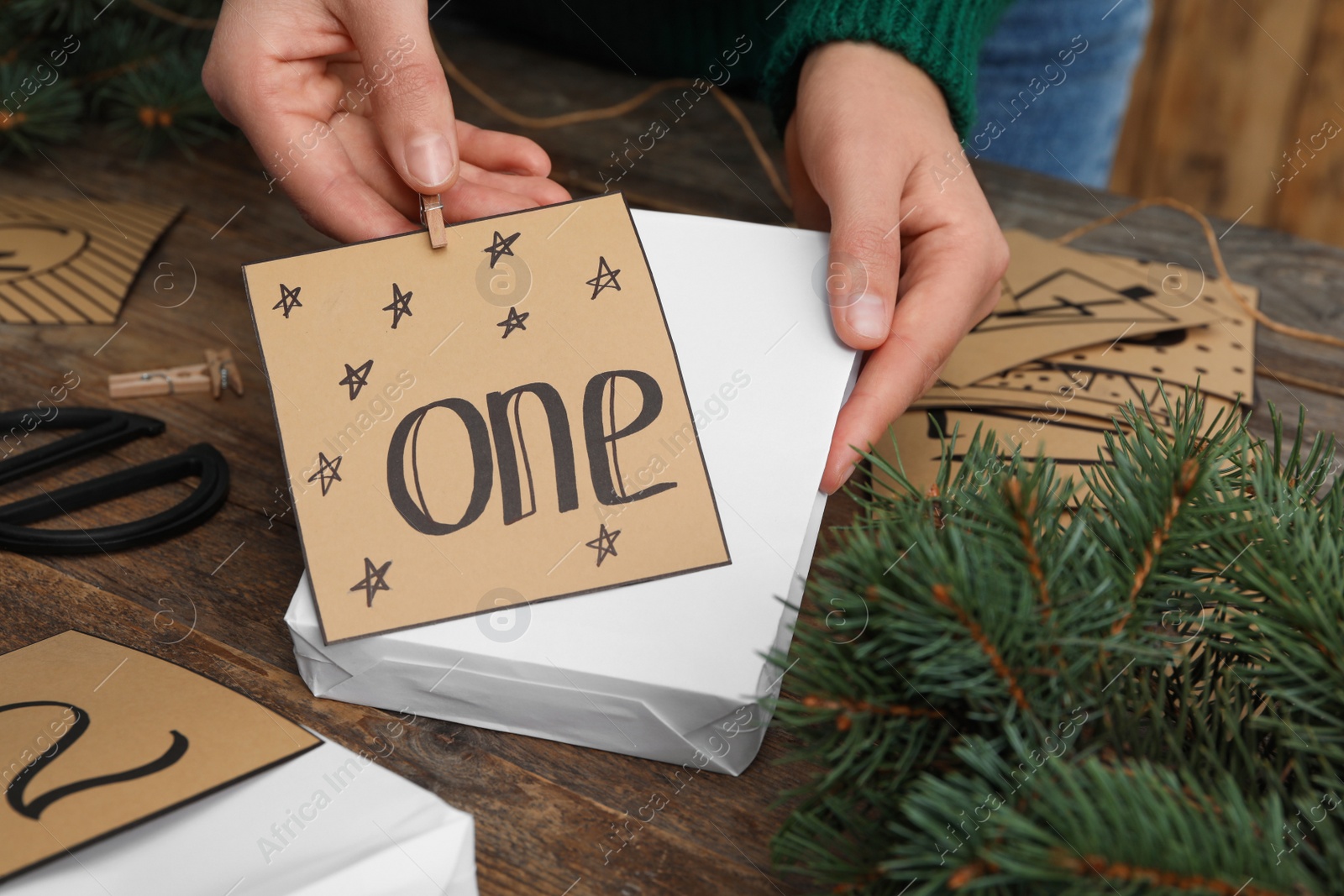 Photo of Woman making advent calendar at wooden table, closeup