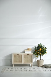 Photo of Wooden commode near white wall in room. Interior design