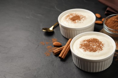 Photo of Delicious semolina pudding with cinnamon on black table, space for text