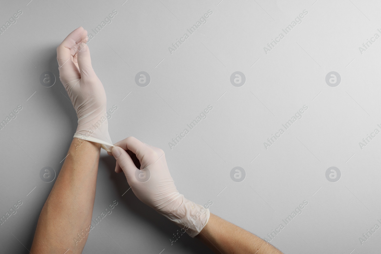 Photo of Doctor wearing white medical gloves on grey background, top view. Space for text