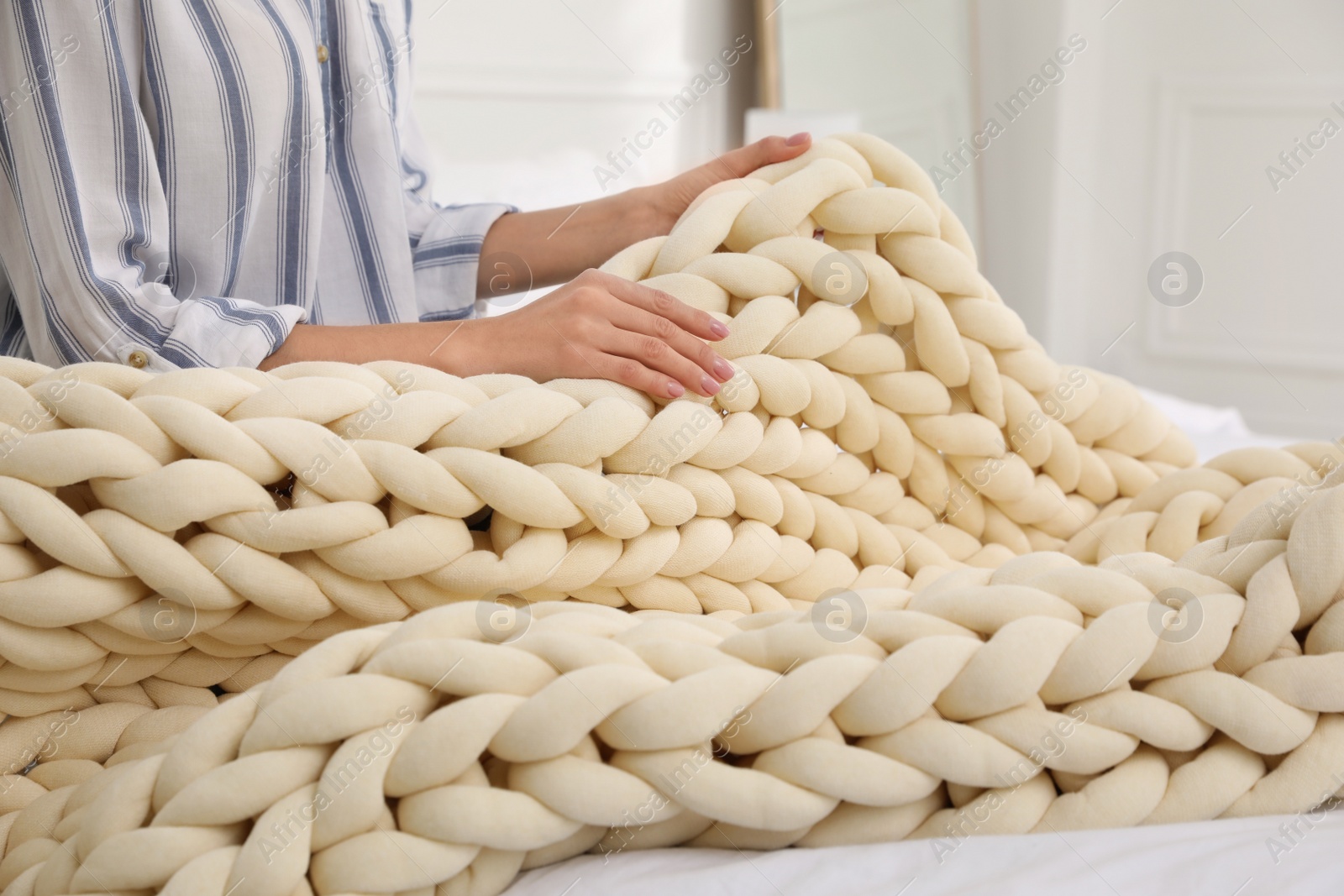 Photo of Woman with chunky knit blanket at home, closeup