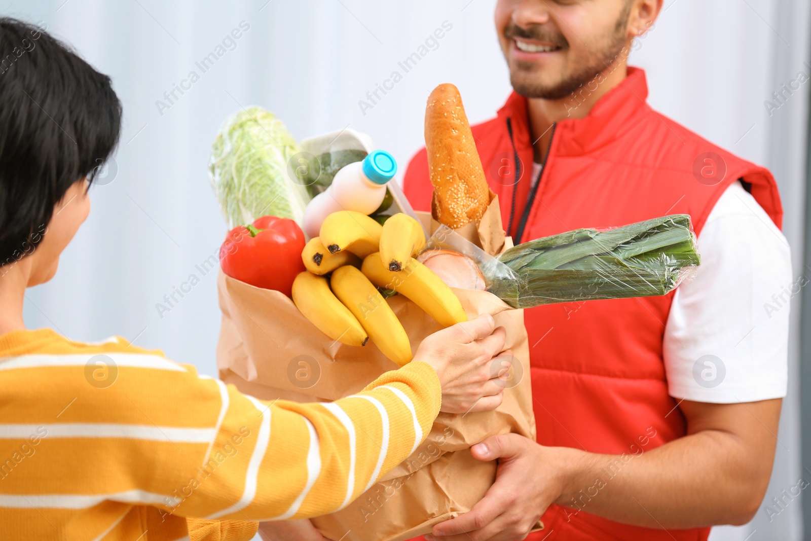 Photo of Male courier delivering food to client on light background, closeup