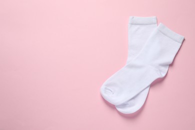 Photo of Pair of white socks on pink background, flat lay. Space for text